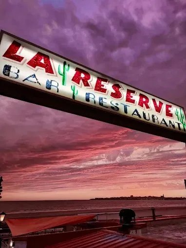 Enseigne La Réserve sous un ciel rose et violet